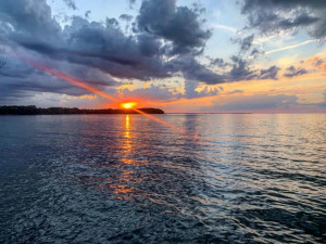 sunset on kelleys island with water in the foreground and clouds in the sky