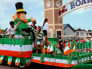 St. Patrick's Day parade float with leprechaun and Irish flags.